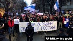 Hundreds of protesters, many of them expatriate Russians who fled the country rally to mark 10 months since Russia invaded Ukraine in Belgrade in December 2022. The Russian banner at the front says, "Peace for Ukraine, freedom for Russia."
