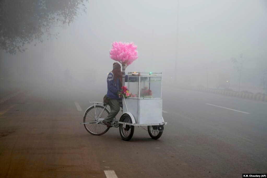 Një shitës i karameleve prej pambuku pret për konsumatorët potencialë teksa mjegulla shtrihet mbi Lahore të Pakistanit.