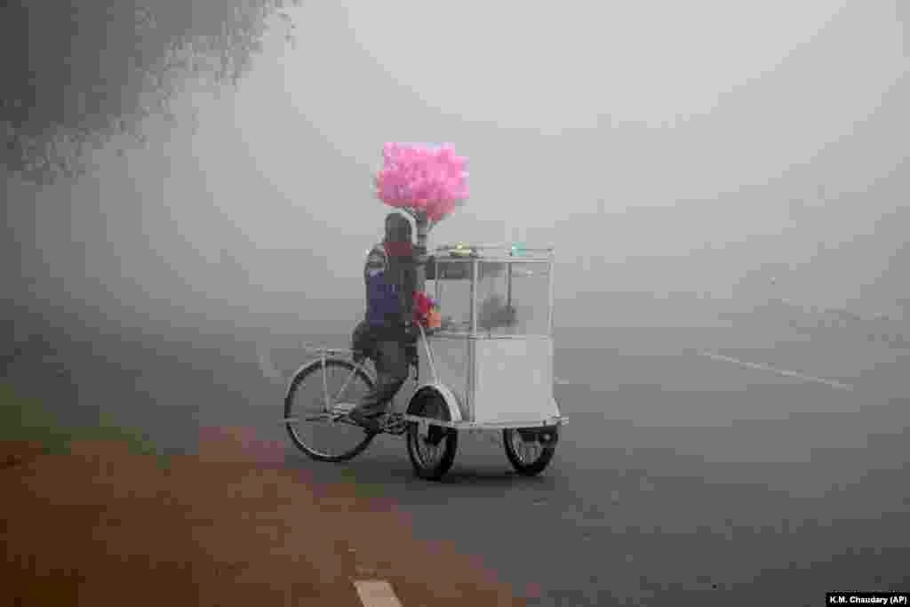A cotton-candy seller waits for customers on a road as heavy fog reduces visibility in Lahore, Pakistan.&nbsp;