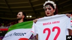 Iran fans hold a "Women, life, freedom" Iranian flag and a replica shirt in memory of Mahsa Amini inside the stadium in Qatar before the match with Wales on November 25.