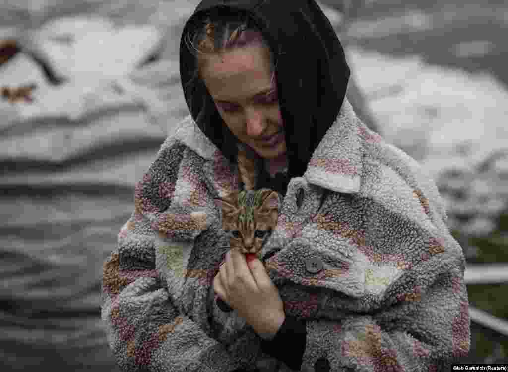 A woman carries a kitten found in a residential building destroyed by a Russian missile attack in the town of Vyshhorod, near Kyiv.