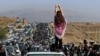 IRAN -- This UGC image posted on Twitter reportedly on October 26, 2022 shows an unveiled woman standing on top of a vehicle as thousands make their way towards Aichi cemetery in Saqez, Mahsa Amini's home town in the western Iranian province of Kurdistan