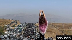 IRAN -- This UGC image posted on Twitter reportedly on October 26, 2022 shows an unveiled woman standing on top of a vehicle as thousands make their way towards Aichi cemetery in Saqez, Mahsa Amini's home town in the western Iranian province of Kurdistan