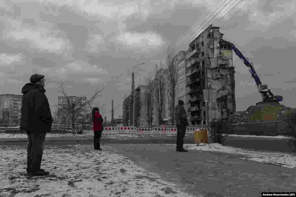 Residents watch as a bombed-out building is demolished in Borodyanka, Ukraine, on December 13.