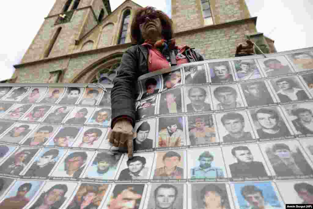 Bosanka sa plakatom na kom su fotografije žrtava genocida u Srebrenici tokom protesta u Sarajevu 11. aprila