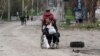A woman pulls a wheelchair while transporting an injured man on a street in the southern port city of Mariupol on April 18.