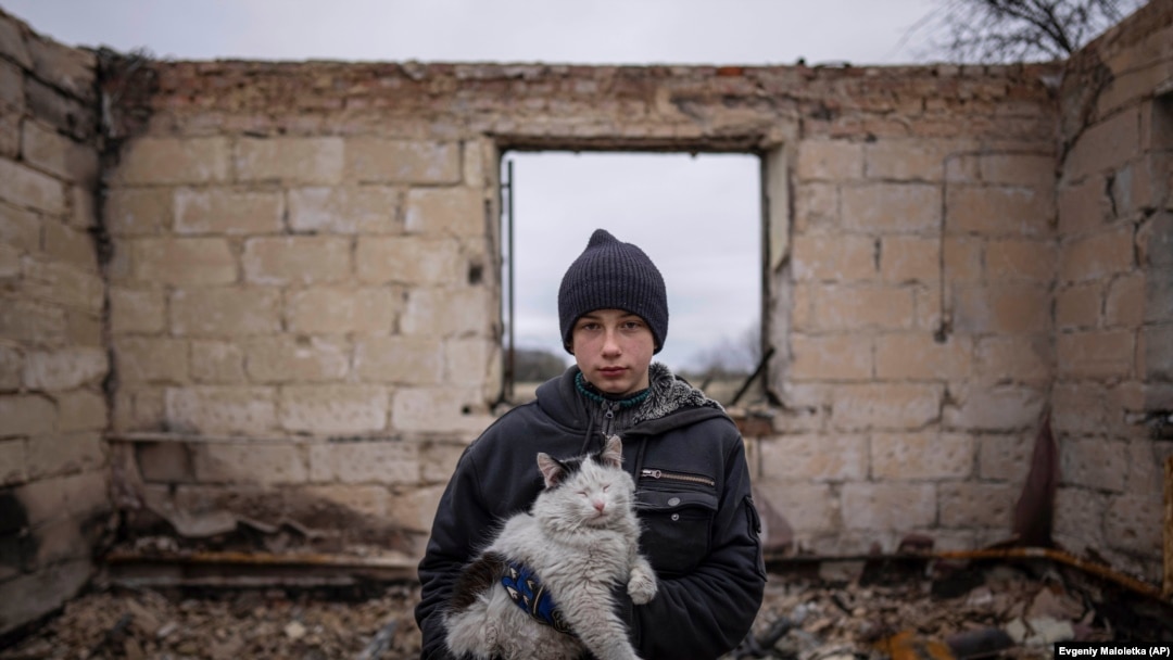 Un băiat de 12 ani din Ucraina ține în brațe o pisică printre dărâmăturile casei sale care a fost distrusă de o bombă a soldaților ruși. Imagine din 13 aprilie 2022, Cernihiv, Ucraina.

