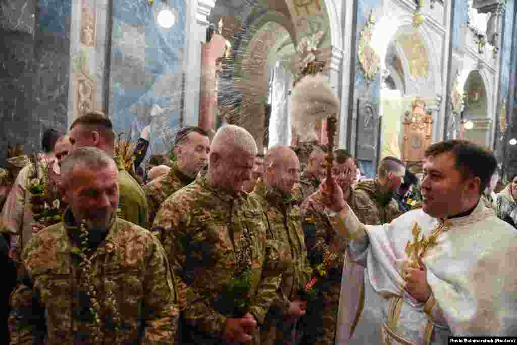 Ukrainian servicemen are sprinkled with holy water as they attend the consecration of willow branches on Palm Sunday at a church in Lviv on April 17.