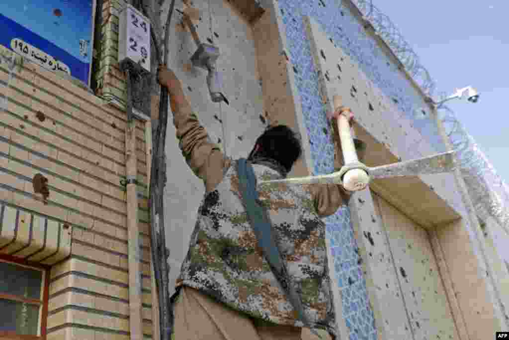 An Afghan protester hits the building of the Iranian Consulate in Herat with a pickax during a demonstration against published reports of harassment of Afghan refugees in Iran on April 11.