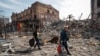 Residents carry their belongings past ruined buildings in the southern port city of Mariupol on April 10.