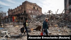 Residents carry their belongings past ruined buildings in the southern port city of Mariupol on April 10.