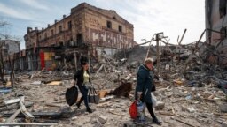 Residents carry their belongings past ruined buildings in the southern port city of Mariupol on April 10.