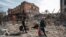 Residents carry their belongings past ruined buildings in the southern port city of Mariupol on April 10.