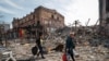 Женщины с тяжелыми сумками передвигаются развалинами Мариуполя, в котором российская армия уничтожила более 90% всех домов. 10 апреля 2022 года