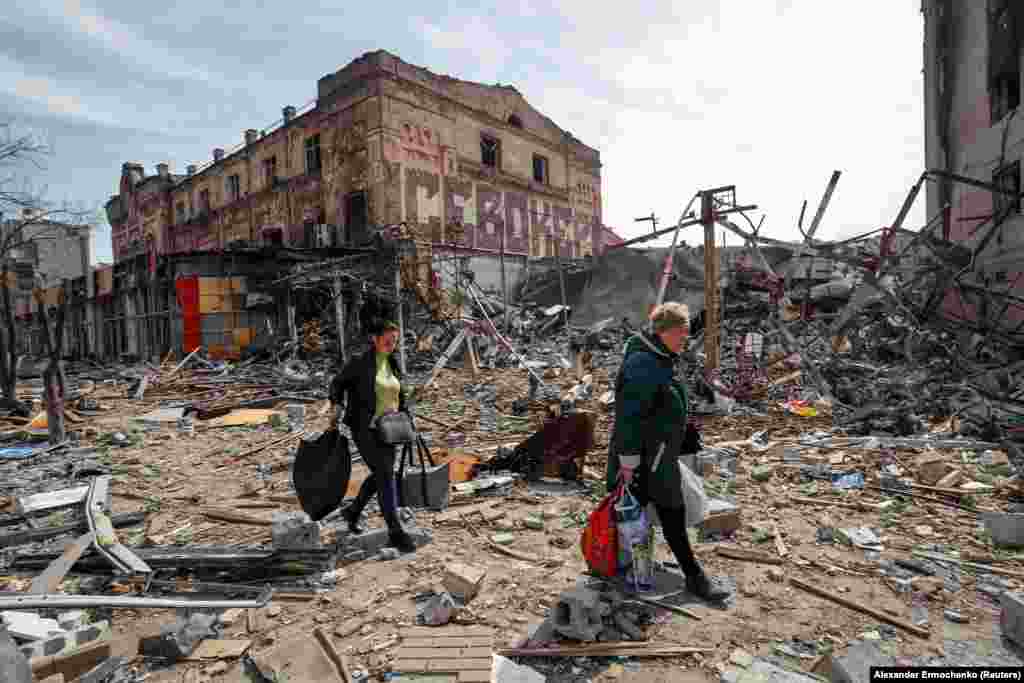 Residents of Mariupol carry their belongings past a destroyed building in the southeastern port city on April 10.&nbsp;