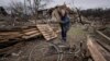 Женщина собирает доски на улице, разрушенной в результате обстрела в Чернигове, 13 апреля 2022 года