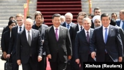Председатель Китая Си Цзиньпин (в центре) и другие лидеры государств — членов и наблюдателей Шанхайской организации сотрудничества, а также представители региональных и международных организаций направляются для групповых фотографий во время встречи в Бишкеке в июне 2019 года