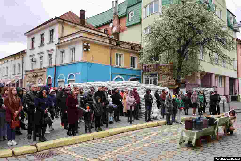 People holding willow branches stand next to sand bags as they celebrate Palm Sunday in Ivano-Frankivsk, western Ukraine, on April 17.