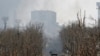 An armored vehicle of Russia&#39;s forces moves down a war-ravaged street in Mariupol on&nbsp; April 12. The massive Soviet-era Azovstal iron and steel works rises in the background.&nbsp;