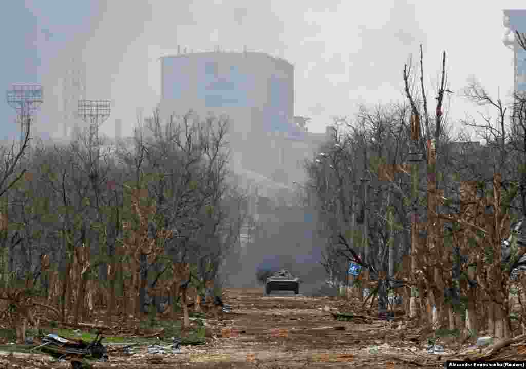 An armored vehicle of Russia&#39;s forces moves down a war-ravaged street in Mariupol on&nbsp; April 12. The massive Soviet-era Azovstal iron and steel works rises in the background.&nbsp;