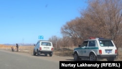 Жол бойында тұрған полиция көлігі, жеңіл көлік және мотоцикл мен жүргізуші (Азаттық архивіндегі фото)