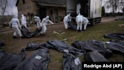 Ексгумовані тіла загиблих у Бучі цивільних завантажують для перевезення до моргу, Буча, 12 квітня 2022 року