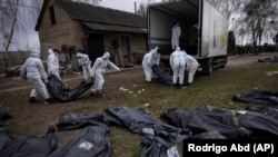 Ексгумовані тіла загиблих у Бучі цивільних завантажують для перевезення до моргу, Буча, 12 квітня 2022 року