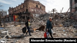 Stanovnici nose svoje stvari u blizini zgrada uništenih ruskim granatiranjem u Mariupolju 10. aprila.