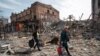 Residents carry their belongings near buildings destroyed by Russian shelling in Mariupol on April 10.