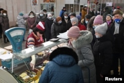 Vásárlók sora egy élelmiszerpult mellett egy omszki piacon februárban