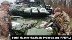 Украинские военные рядом с подбитым российским танком в Донецкой области Украины. 13 апреля 2022 года