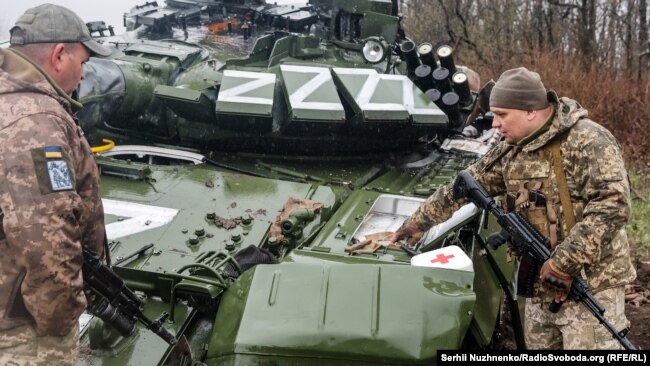 Украинские военные рядом с подбитым российским танком в Донецкой области Украины. 13 апреля 2022 года