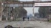 Two people on bicycles and a dead body on devastated street in Mariupol_Ukraine
