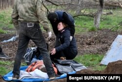 O femeie din Andrivka, regiunea Kiev, își plânge soțul găsit într-o groapă sumară de lângă casa lor. Imagine din 11 aprilie.