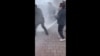 Полицейские тушат огонь после самосожжения женщины у здания МВД в Астане. Кадр из видео