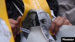 Armenia - An opposition protester in Yerevan rips a poster depicting Serzh Sarkisian and his 2014 promise not to hold on to power, 13 April 2018.