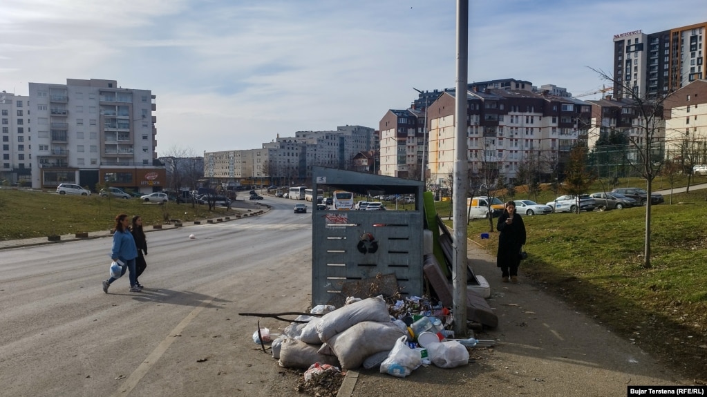 Një qytetare shihet duke ecur drejt një kontejneri për të hedhur një qese me mbeturina në Prishtinë.