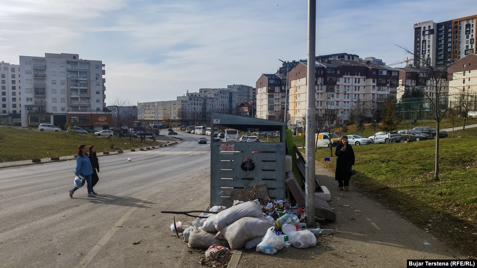 Një qytetare shihet duke ecur drejt një kontejneri për të hedhur një qese me mbeturina në Prishtinë.