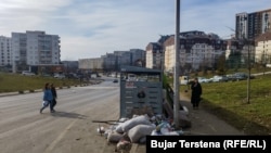 Një qytetare shihet duke ecur drejt një kontejneri për të hedhur një qese me mbeturina në Prishtinë.
