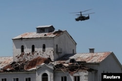 Российский вертолет Ка-52 «Аллигатор» пролетает над разрушенным зданием. Город Попасная Луганской области, Украина, 2 июня 2022 года