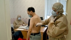 A doctor examines a man, suspected of being infected with the coronavirus, at a clinic in the town of Irpin outside Kyiv.