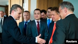 European Energy Commissioner Guenther Oettinger (left) reaches out to shake hands with Gazprom Chief Executive Aleksei Miller (second from right) as Gazprom representative Sergey Kupriyanov (center) looks on after EU-Ukraine-Russia energy negotiations at the EU commission representation in Berlin on May 30.