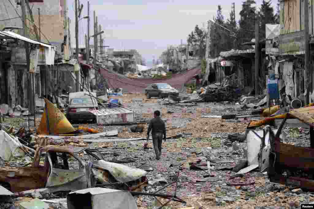 A man walks in a street with abandoned vehicles and and damaged buildings in the northern Syrian town of Kobani on January 30. (Reuters/Osman Orsal)