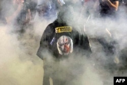 Demonstrant u odjeći koja prikazuje izraelskog premijera, hoda kroz dim na protestima u Tel Avivu 26. maja 2024.