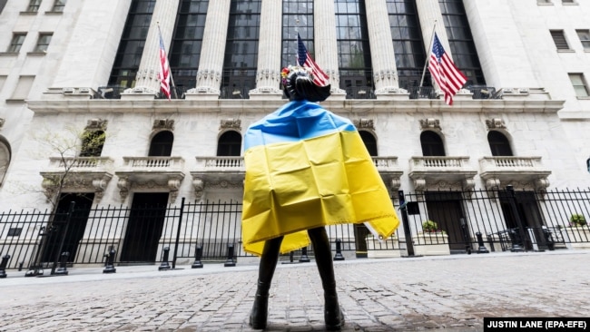 Український прапор на статуї «Безстрашної дівчинки» в Нью-Йорку перед фондовою біржею під час акції із закликом до компаній припинити ведення бізнесу в Росії. Нью-Йорк, США, 4 травня 2022 року