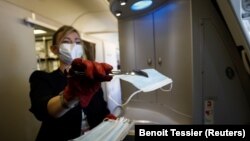 Një punëtore e linjës ajrore Air France u shpërndanë maska mbrojtëse pasagjerëve. 