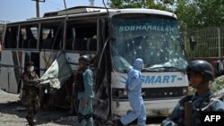 Afghan police and security personnel inspect the scene of a suicide attack on a bus that was transporting employees of the attorney general's office in Kabul, May 4, 2015