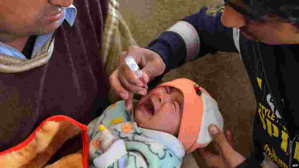 A polio-vaccination worker gives polio vaccine drops to a young girl in Peshawar, Pakistan on December 19. (AFP/A. Majeed)