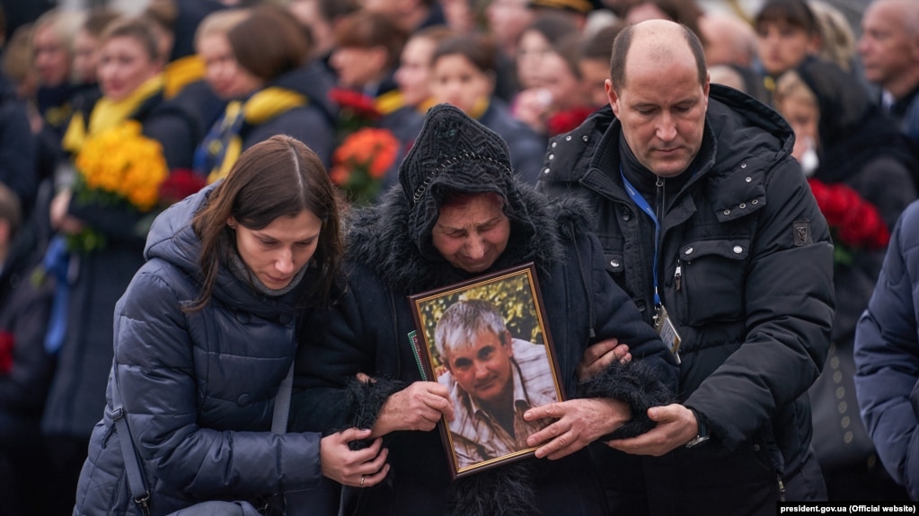 عکس ولادیمیر گاپوننکو، خلبان هواپیمای اوکراینی، در دست خانواده‌اش در مراسم وداع با قربانیان اوکراینی پرواز ۷۵۲