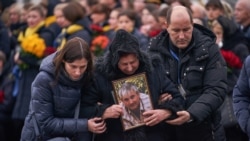 قاب عکس ولودیمیر گاپوننکا، خلبان هواپیمای اوکراینی، در دست مادرش در مراسم وداع با قربانیان اوکراینی پرواز ۷۵۲